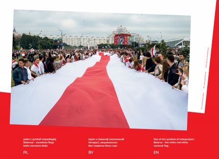 Fotografia z wystawy Białoruś. droga do wolności. tł€m demonstrantów niesie długą wielkowymiarową biało-czerwono-białą flagę narodową białorusi.
